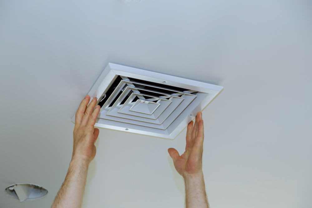 man changing the cover of an air vent grill in home