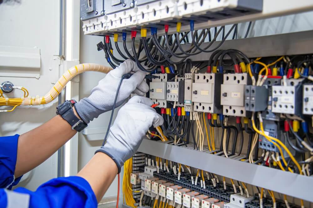 HVAC technician performing maintenance on tripped circuit breaker switchboard