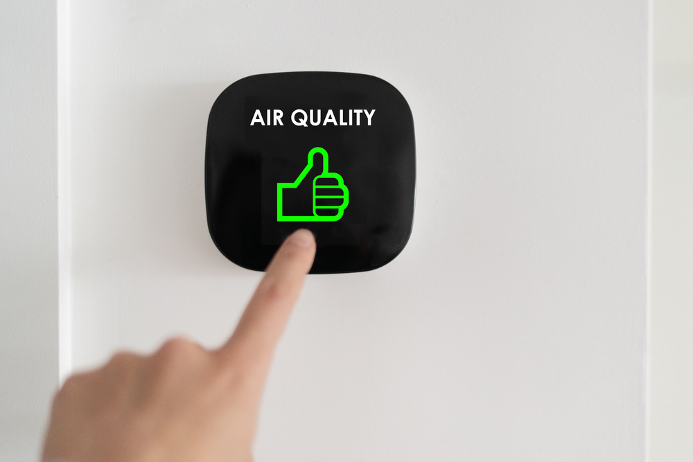 finger pressing a wall-mounted button for indoor air quality