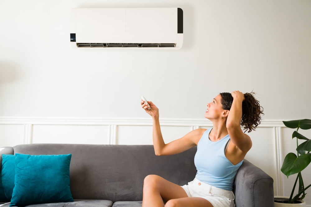 Woman tries to turn on a broken air conditioner with clogged AC drainline