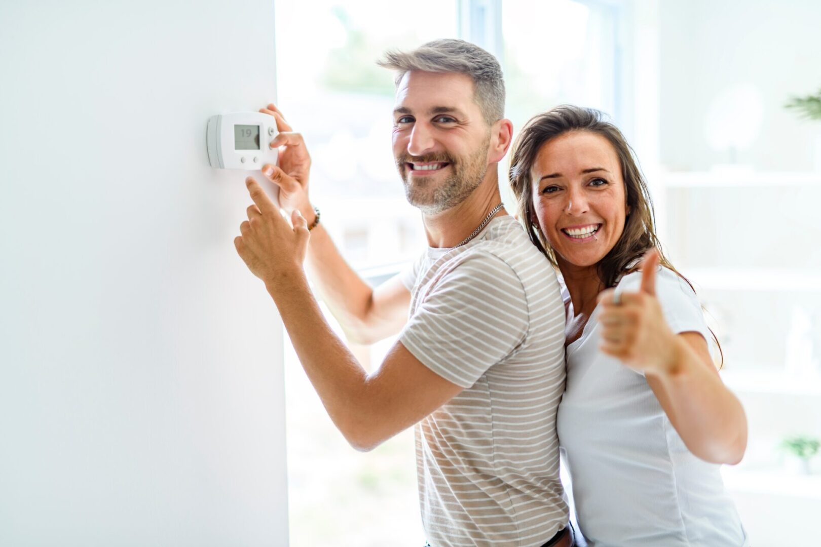 Happy couple using a thermostat to heat their home with Air Authority heating